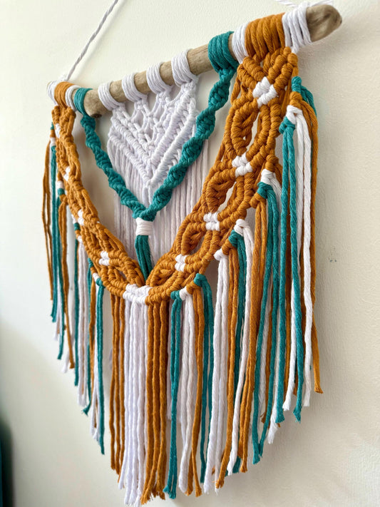 Macrame wall hanging with colorful threads on a white wall