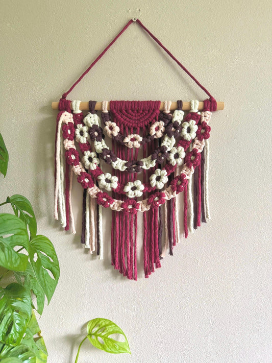 Macrame wall hanging with floral patterns on a plain wall