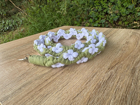 Green and white floral-patterned macrame strap on a wooden surface with a natural background