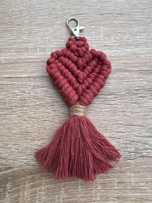 Terracotta macrame heart keychain with tassel on a wooden surface