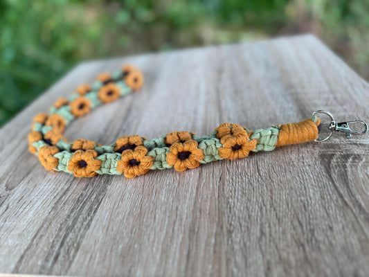 Floral-patterned lanyard on a wooden surface with blurred greenery in the background