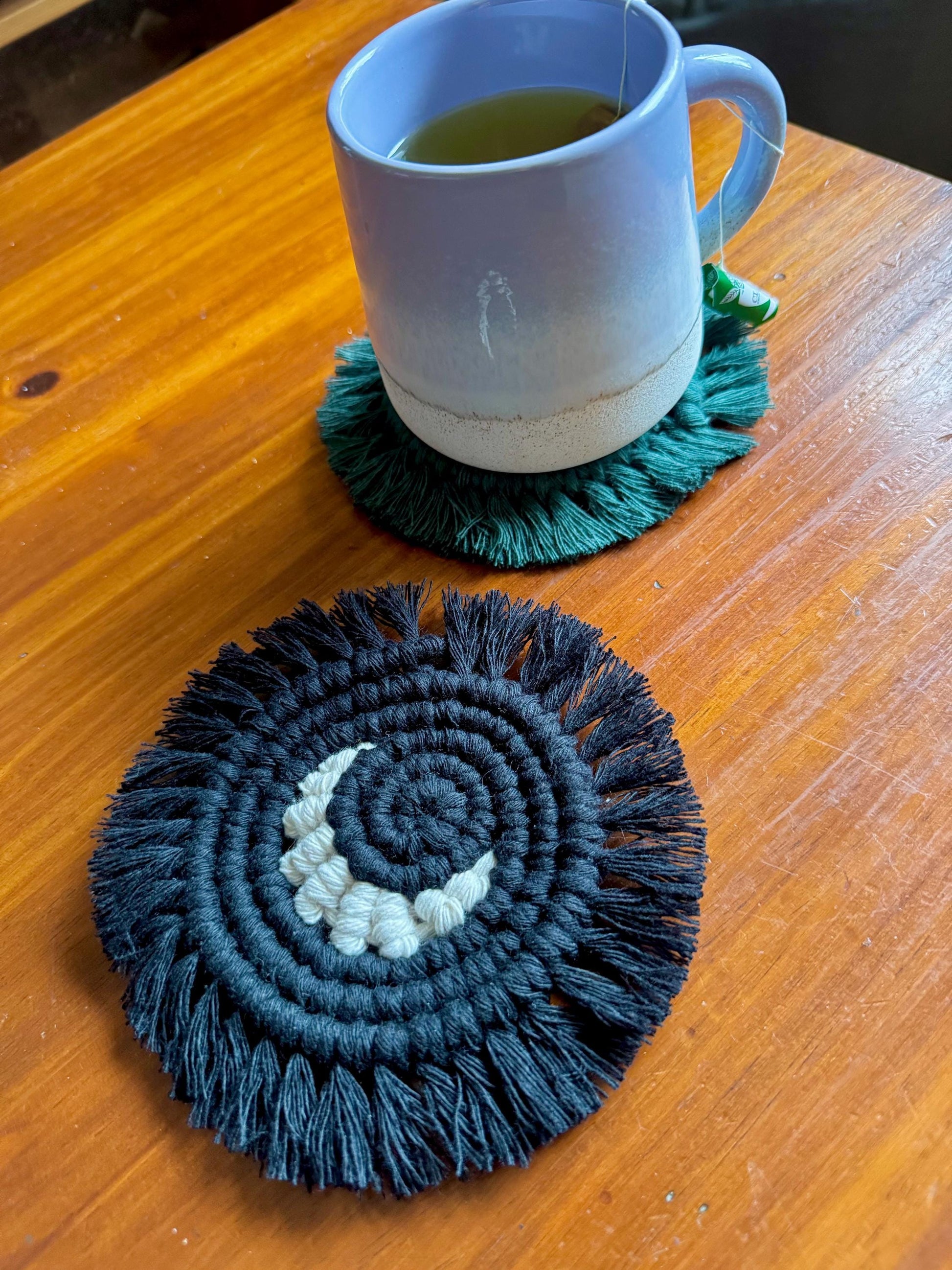 two macrame coasters on a wooden surface