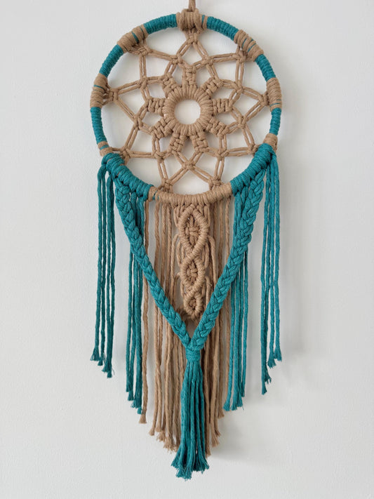 Macrame wall hanging with teal and beige colors on a white background