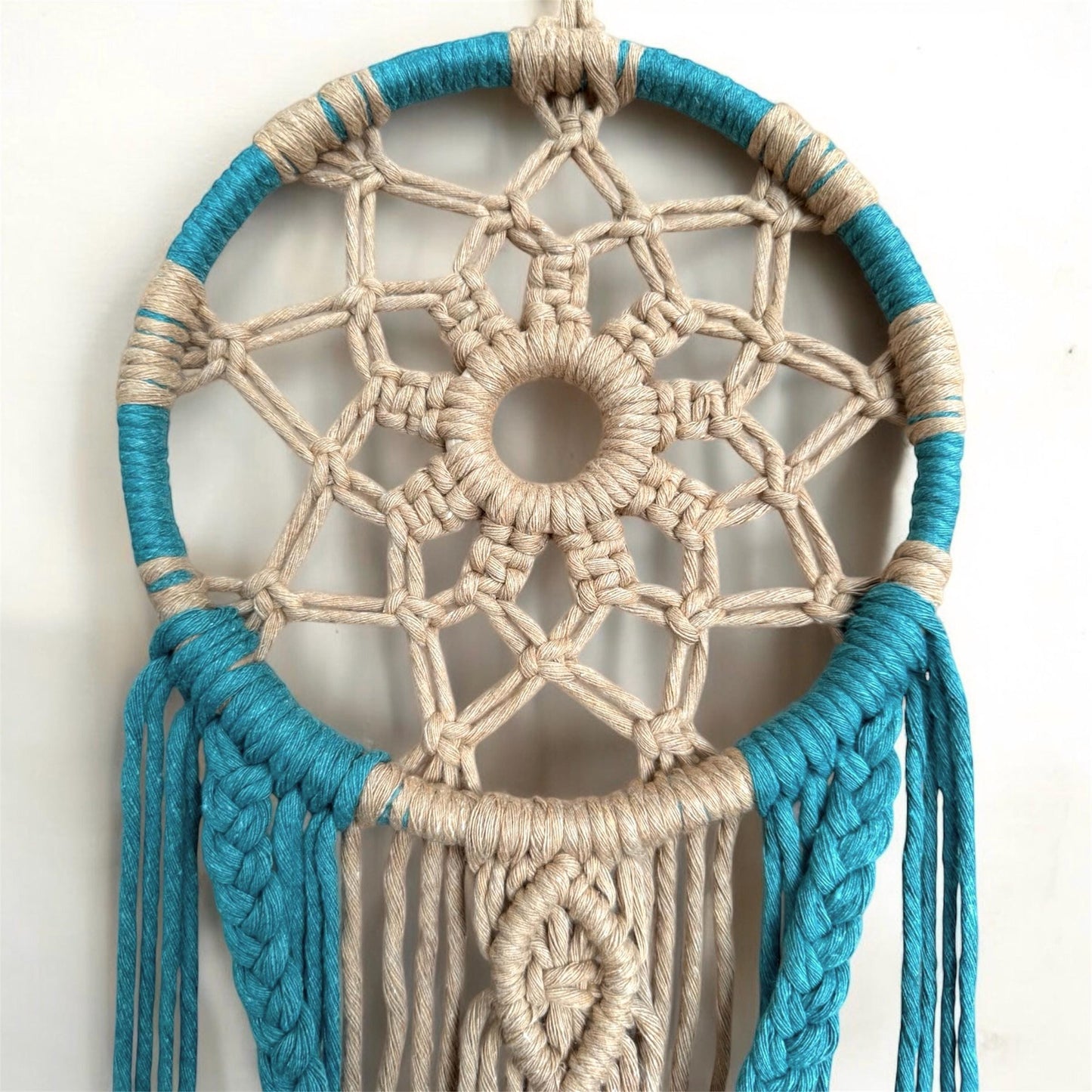 Dreamcatcher with blue and beige cord on a white background