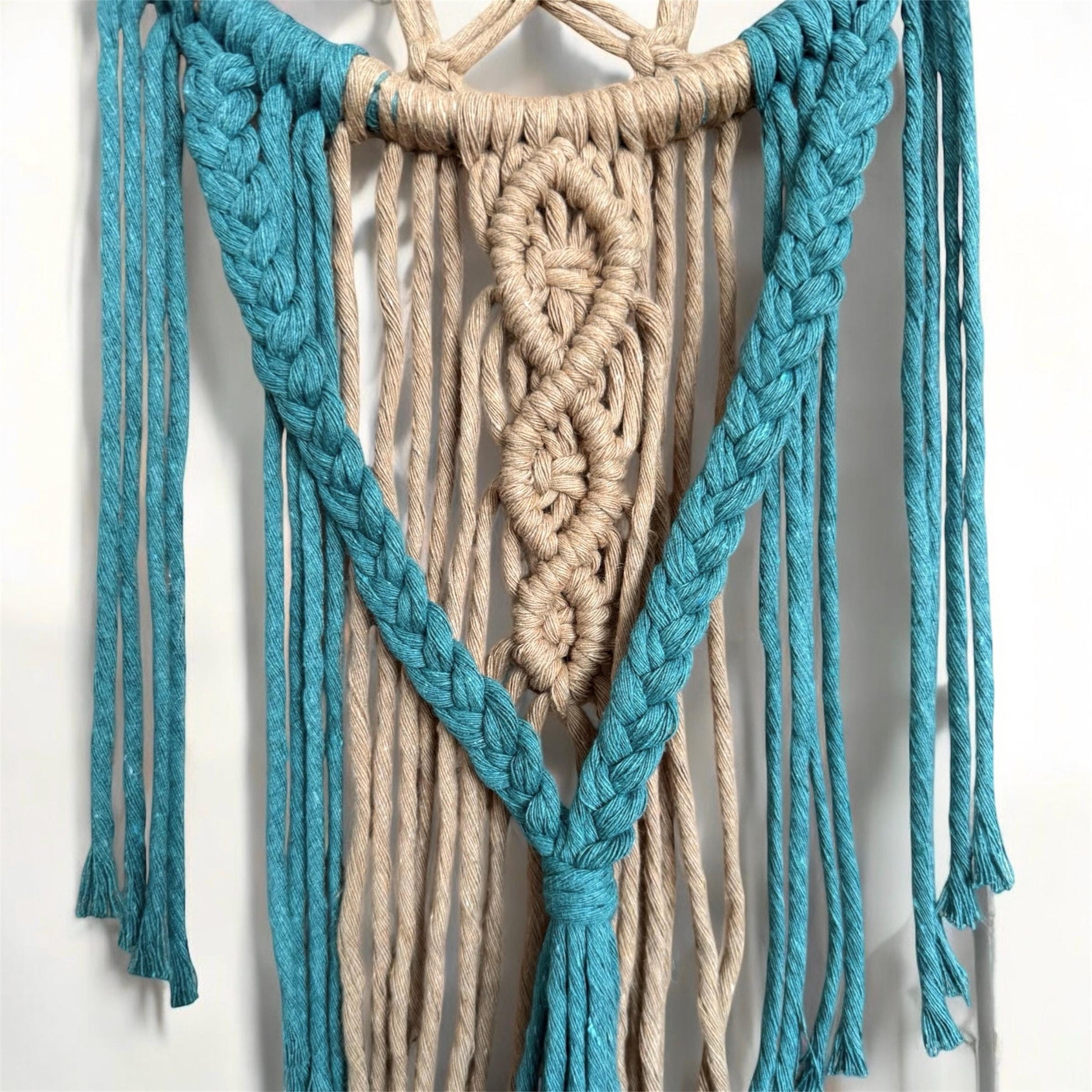Macrame wall hanging with blue and beige ropes on a white background