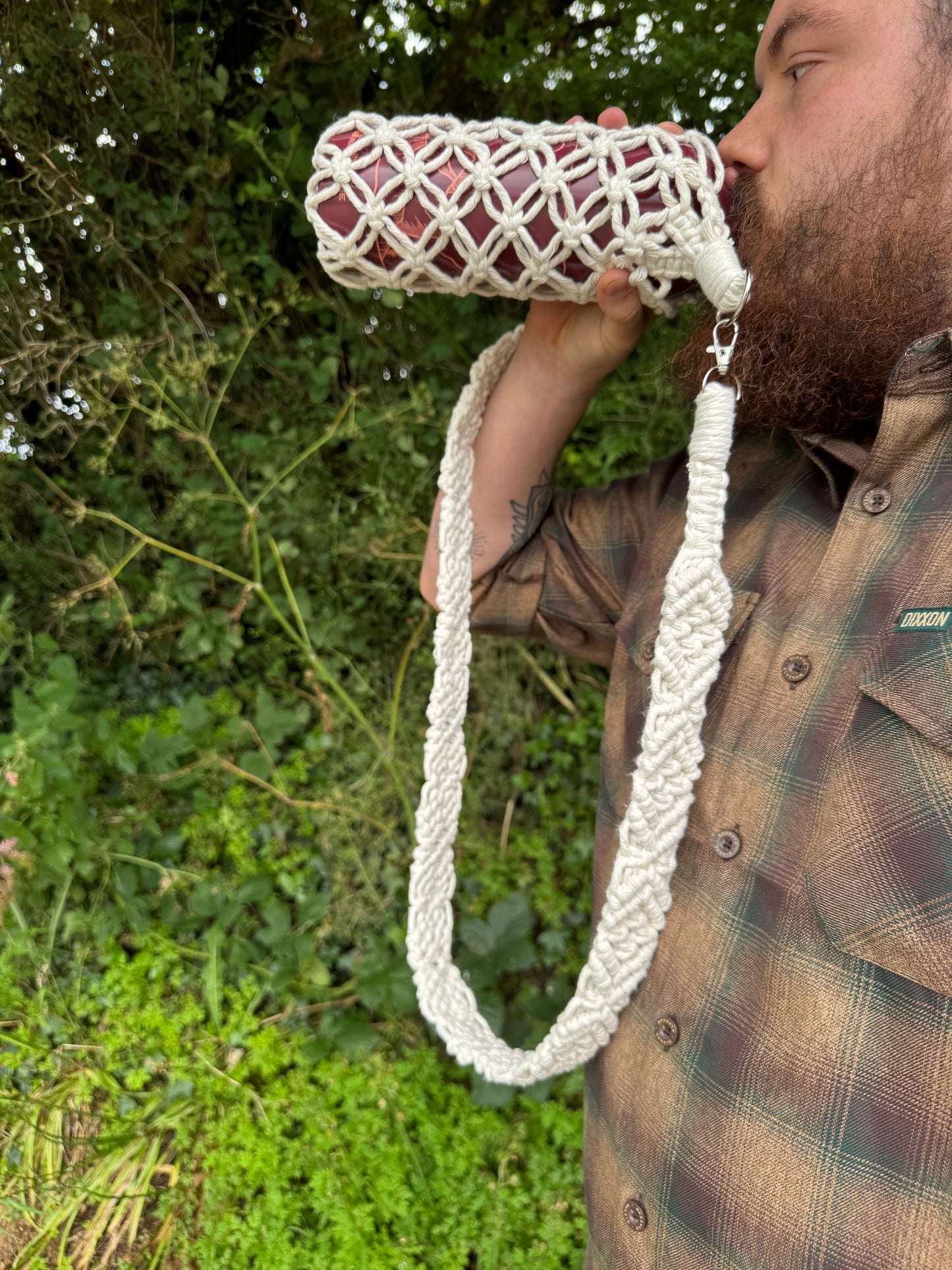 Person holding a white woven bag with a green outdoor background