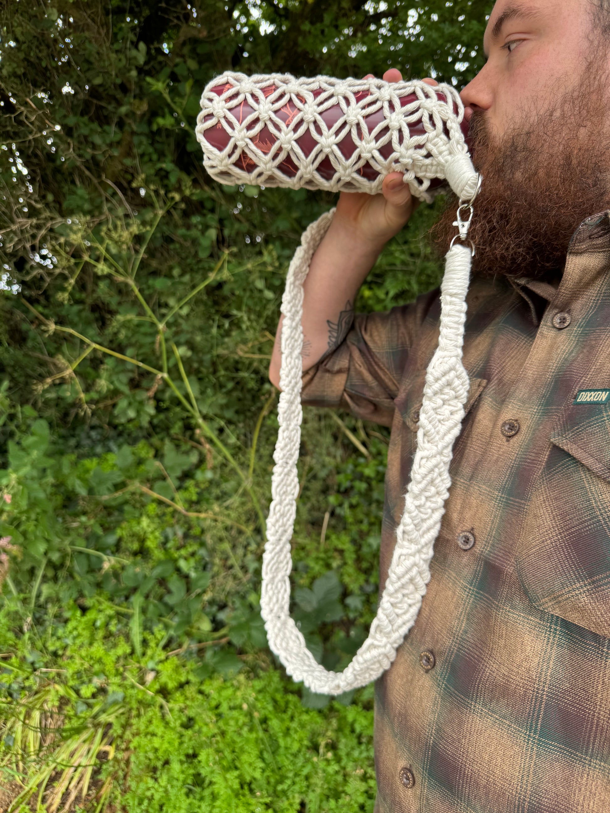Person holding a white woven bag with a green outdoor background