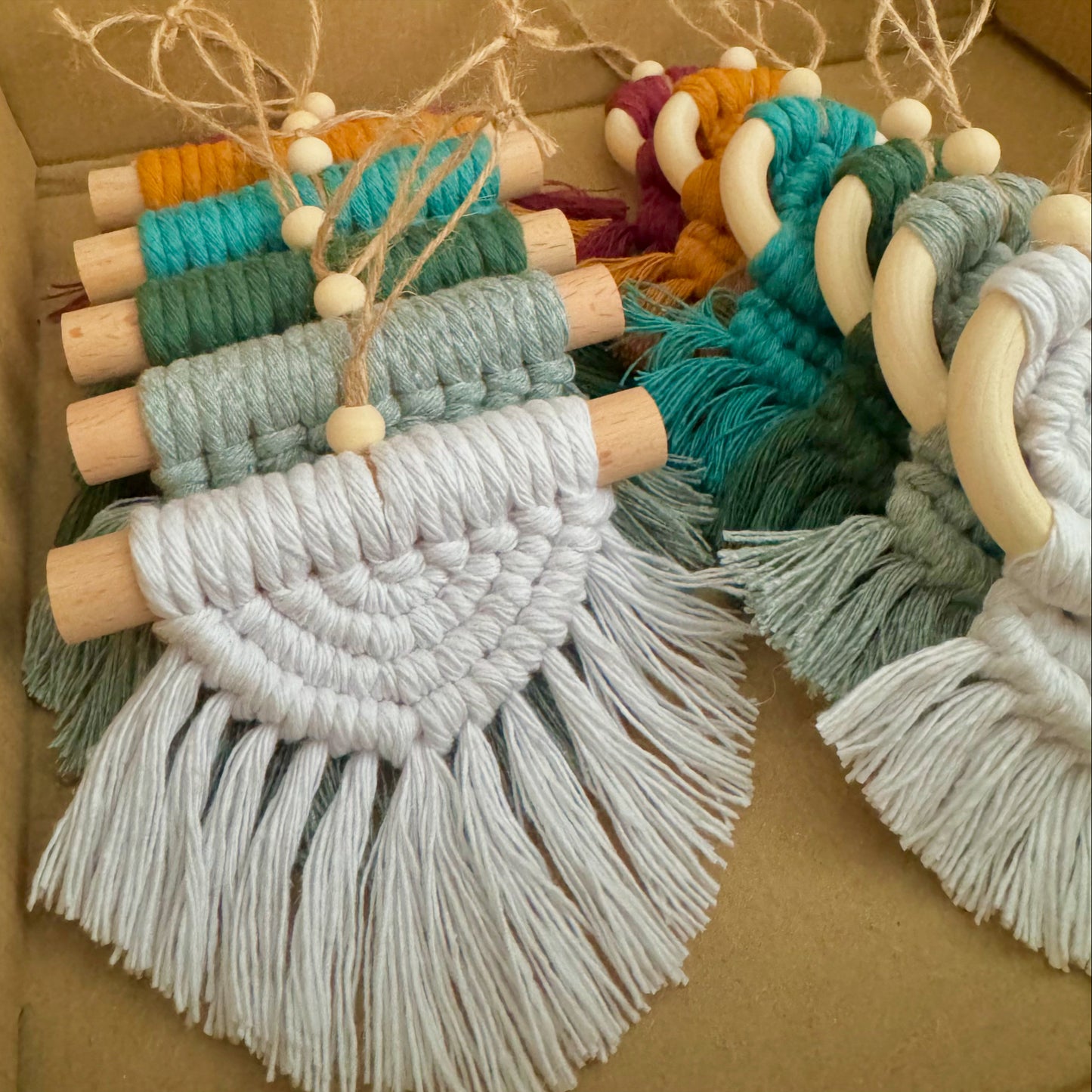 Colorful macrame ornaments with wooden beads on a cardboard background