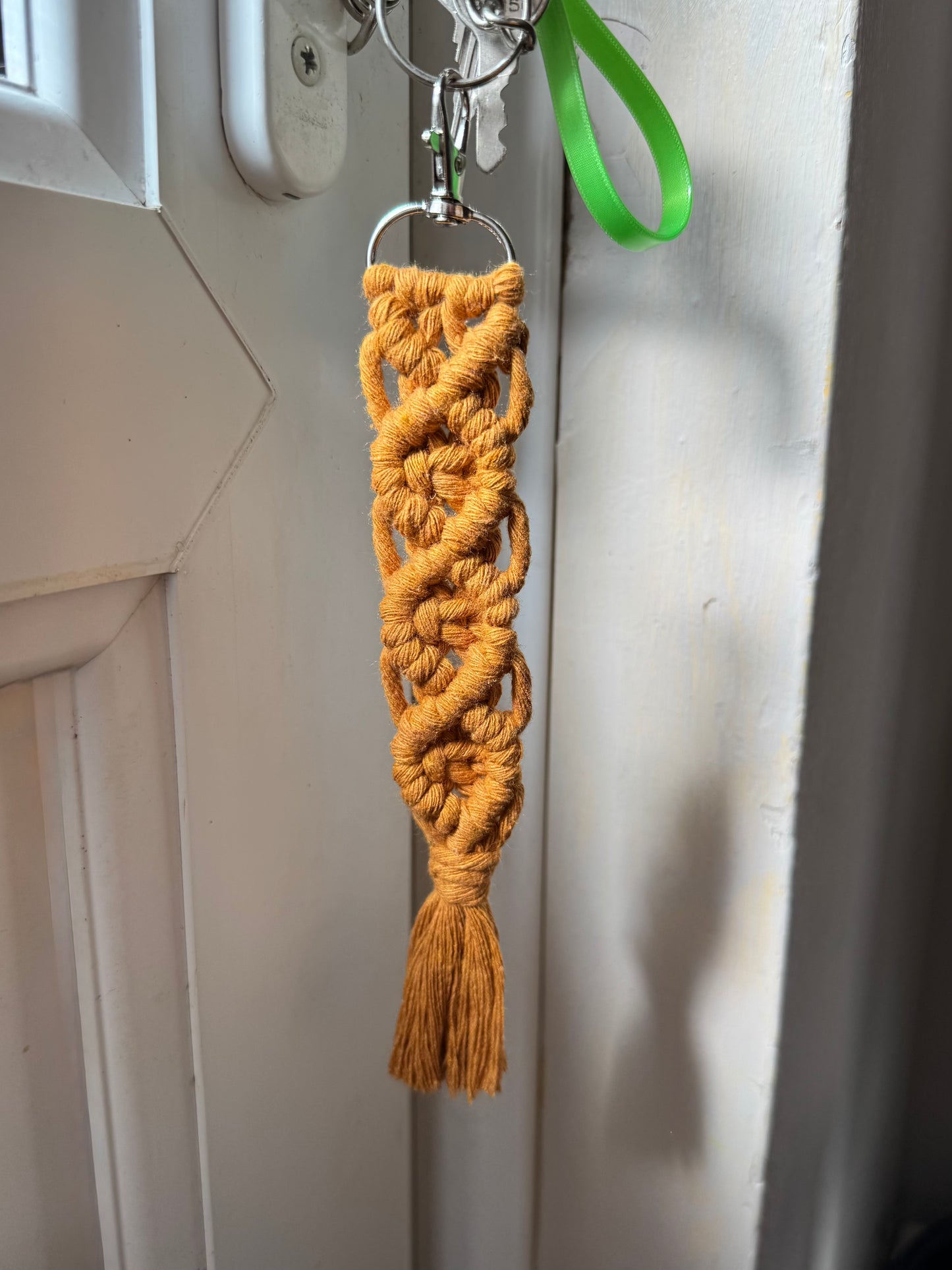 Braided keychain with a tassel hanging on a door handle.
