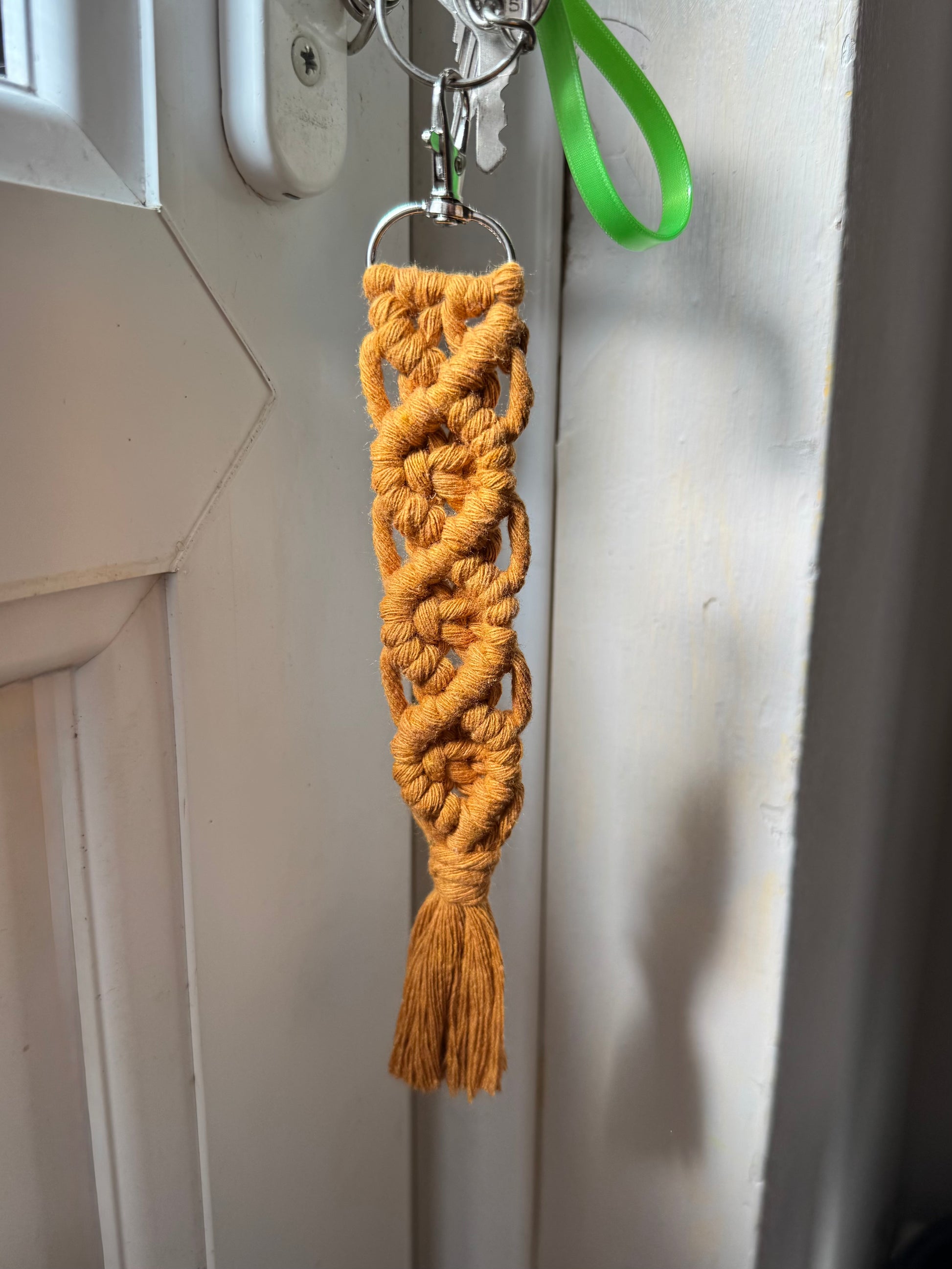 Braided keychain with a tassel hanging on a door handle.