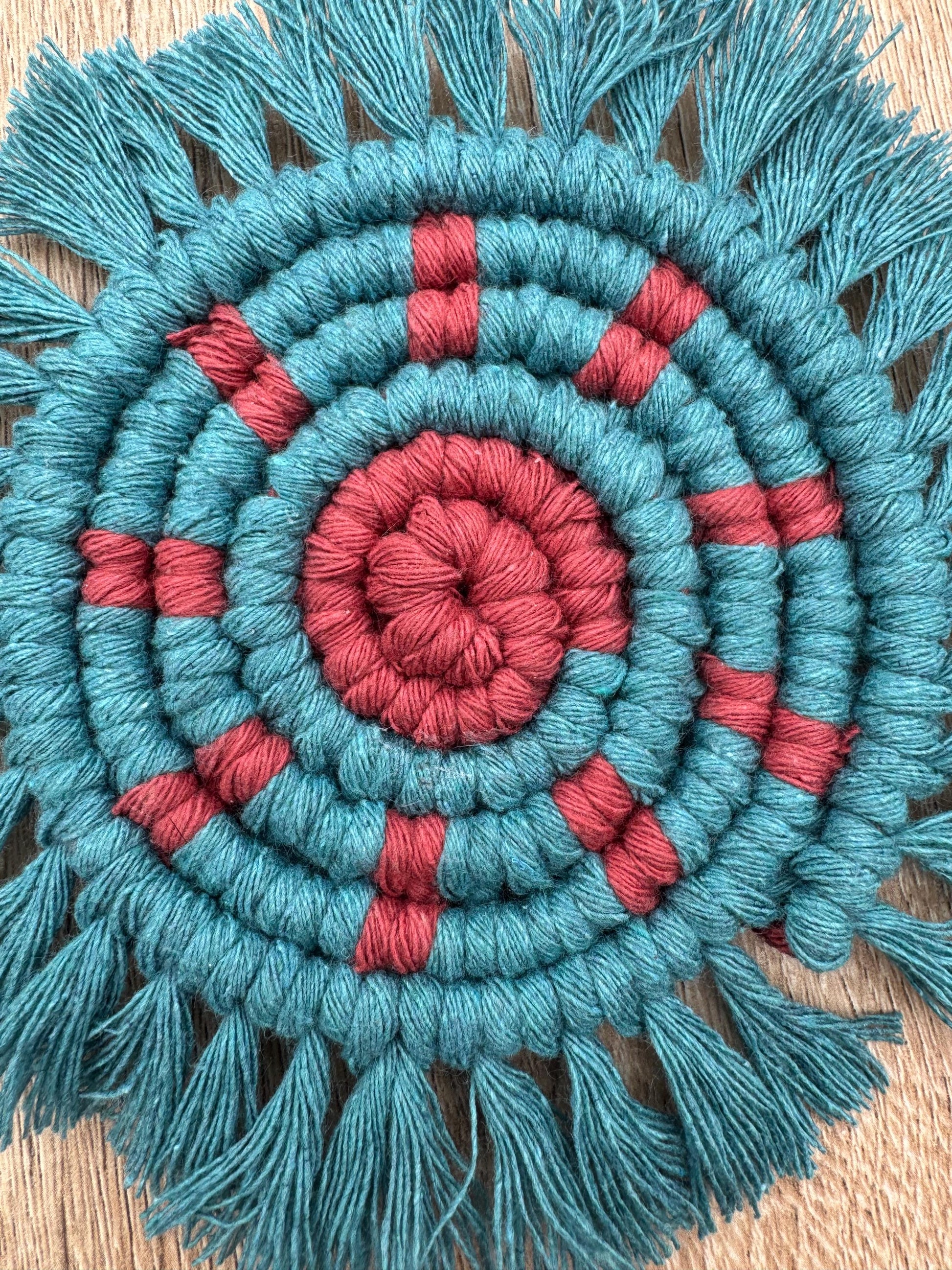 Round woven mat with concentric blue and pink circles on a wooden surface