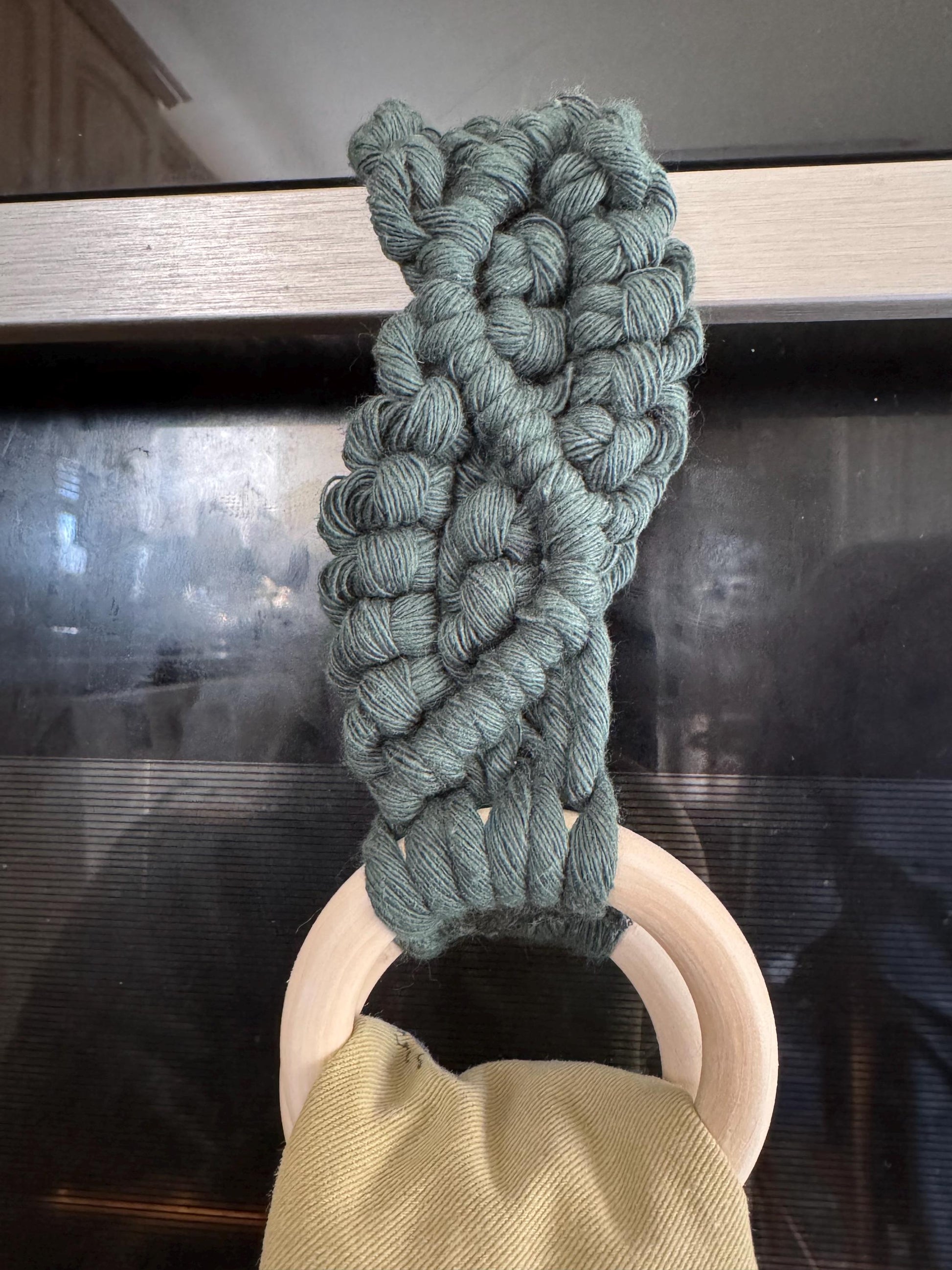 Green braided rope tea towel holder on a glass surface