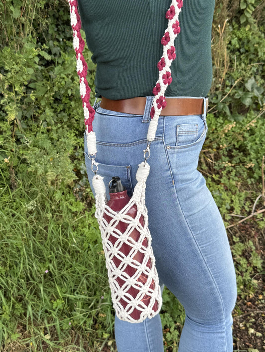 Person holding a macrame bag with floral details over a green outdoor background