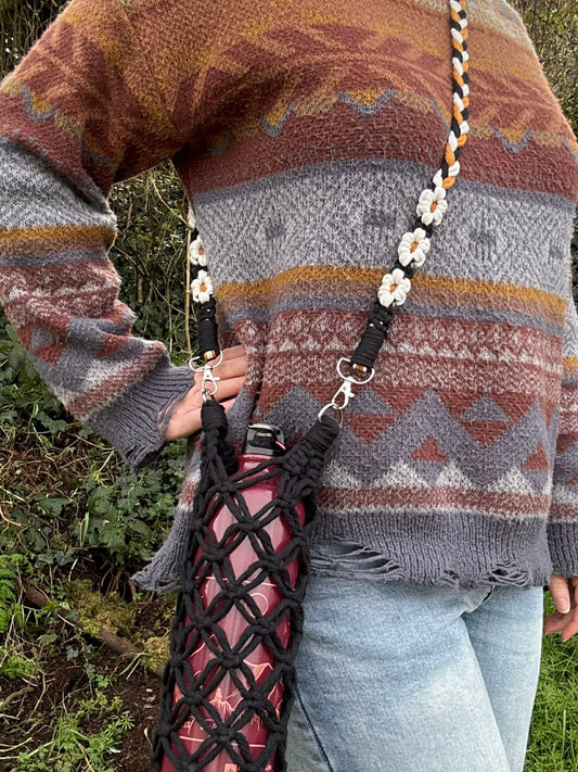 Person wearing a patterned sweater with a macrame bag over their shoulder outdoors.