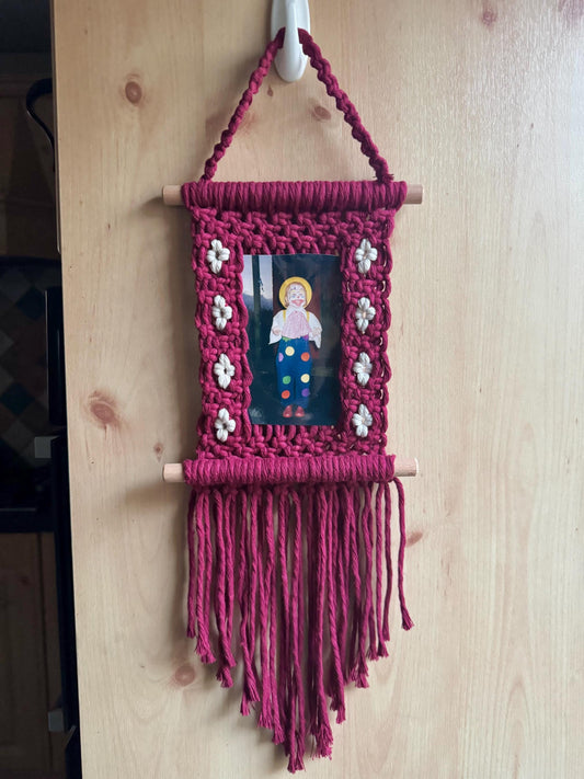 Burgundy floral macrame photo frame with a small picture inside on a wooden door.