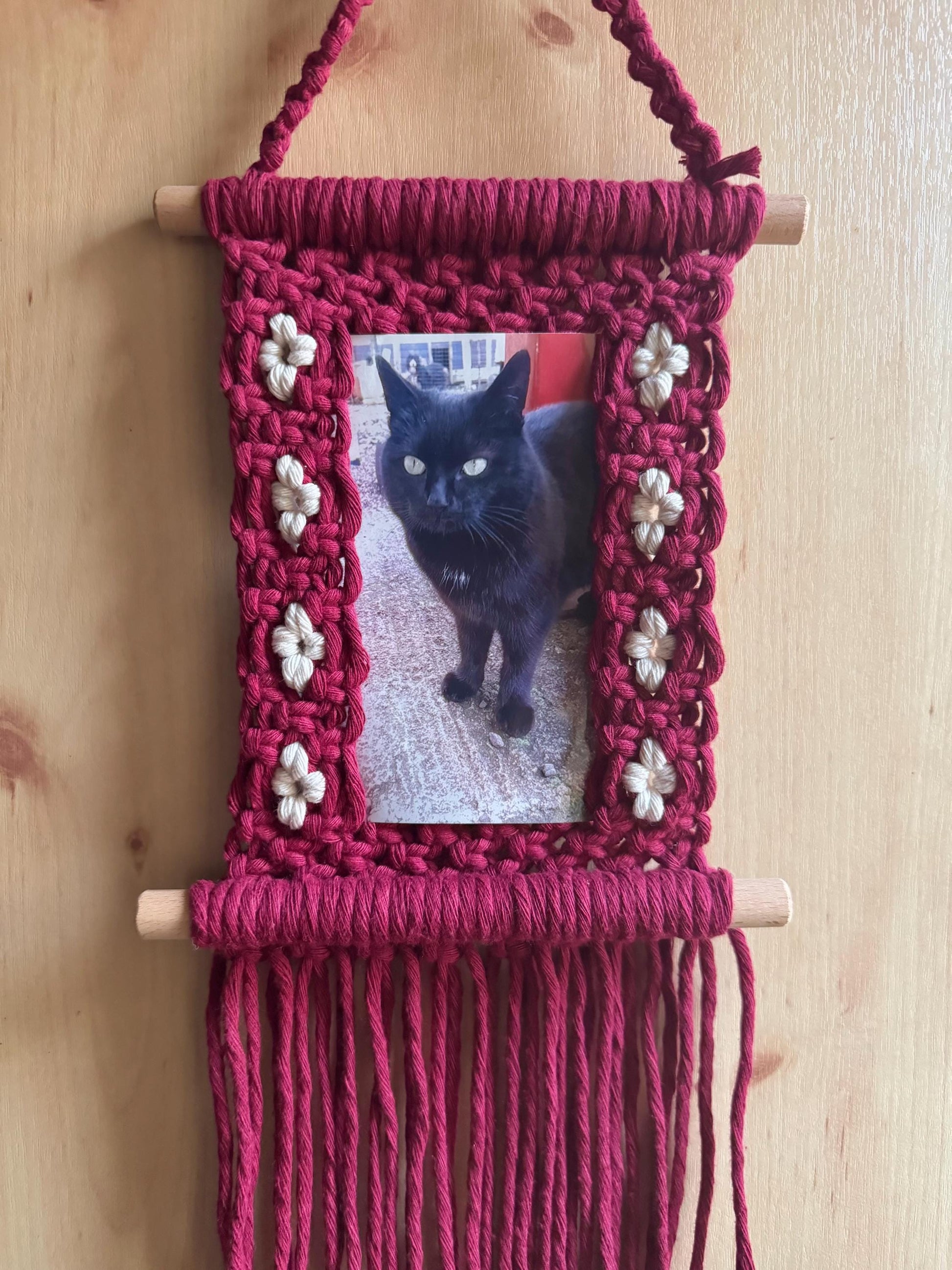 Macrame wall hanging with a photo of a black cat on a wooden background