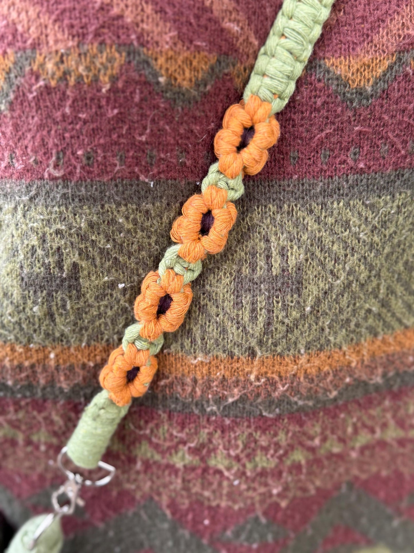Strap with orange and green floral patterns on a textured fabric background