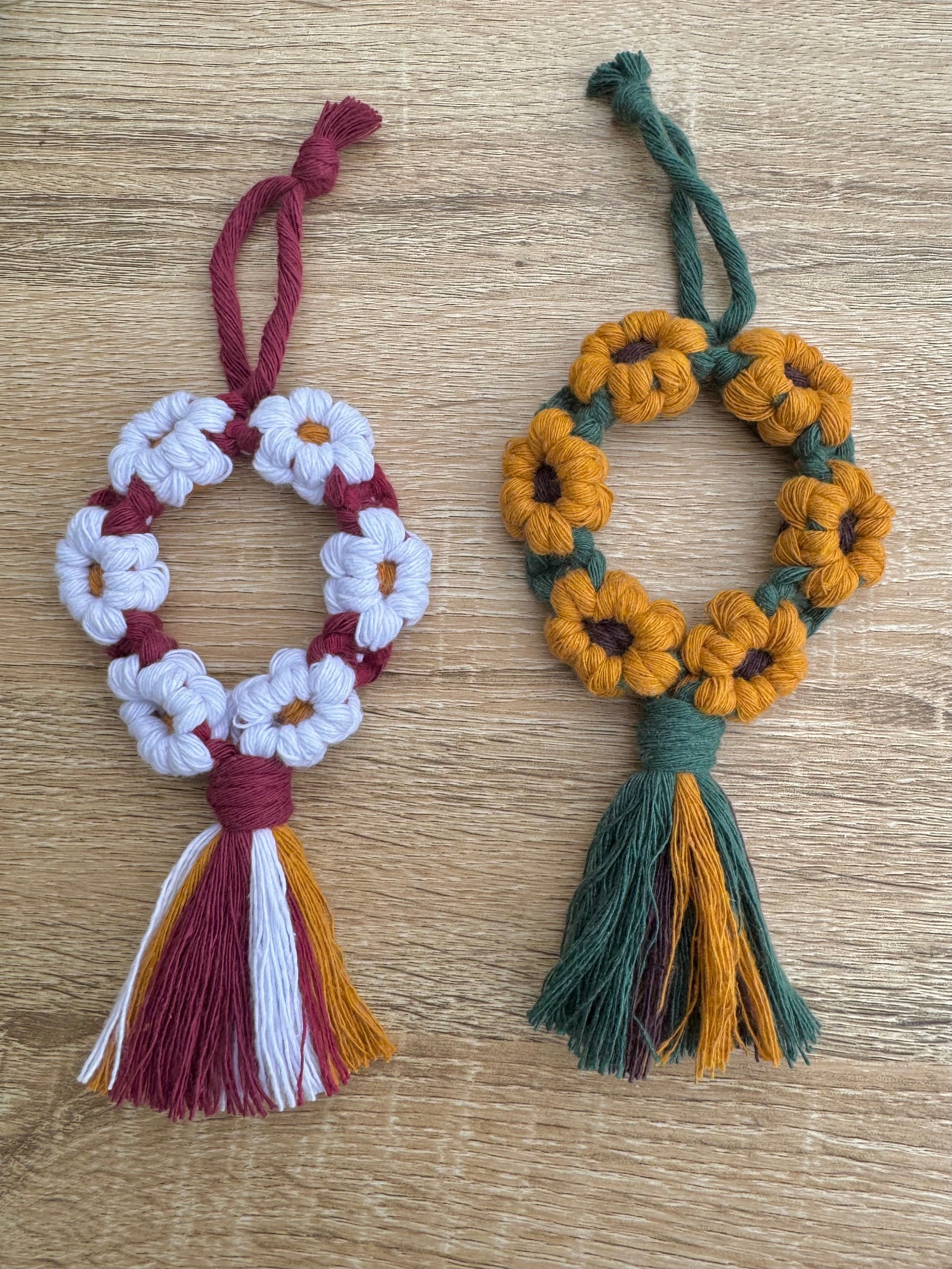 Two macrame flower ornaments with tassels on a wooden surface