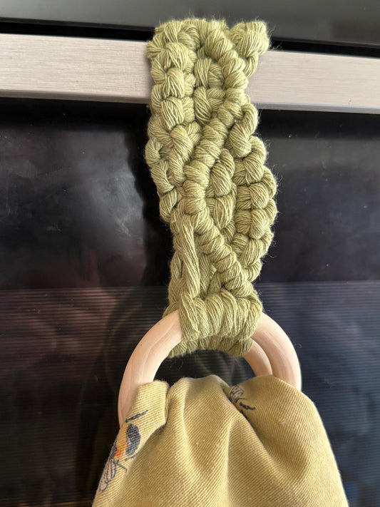 Green macrame attached to a wooden ring with a dark background
