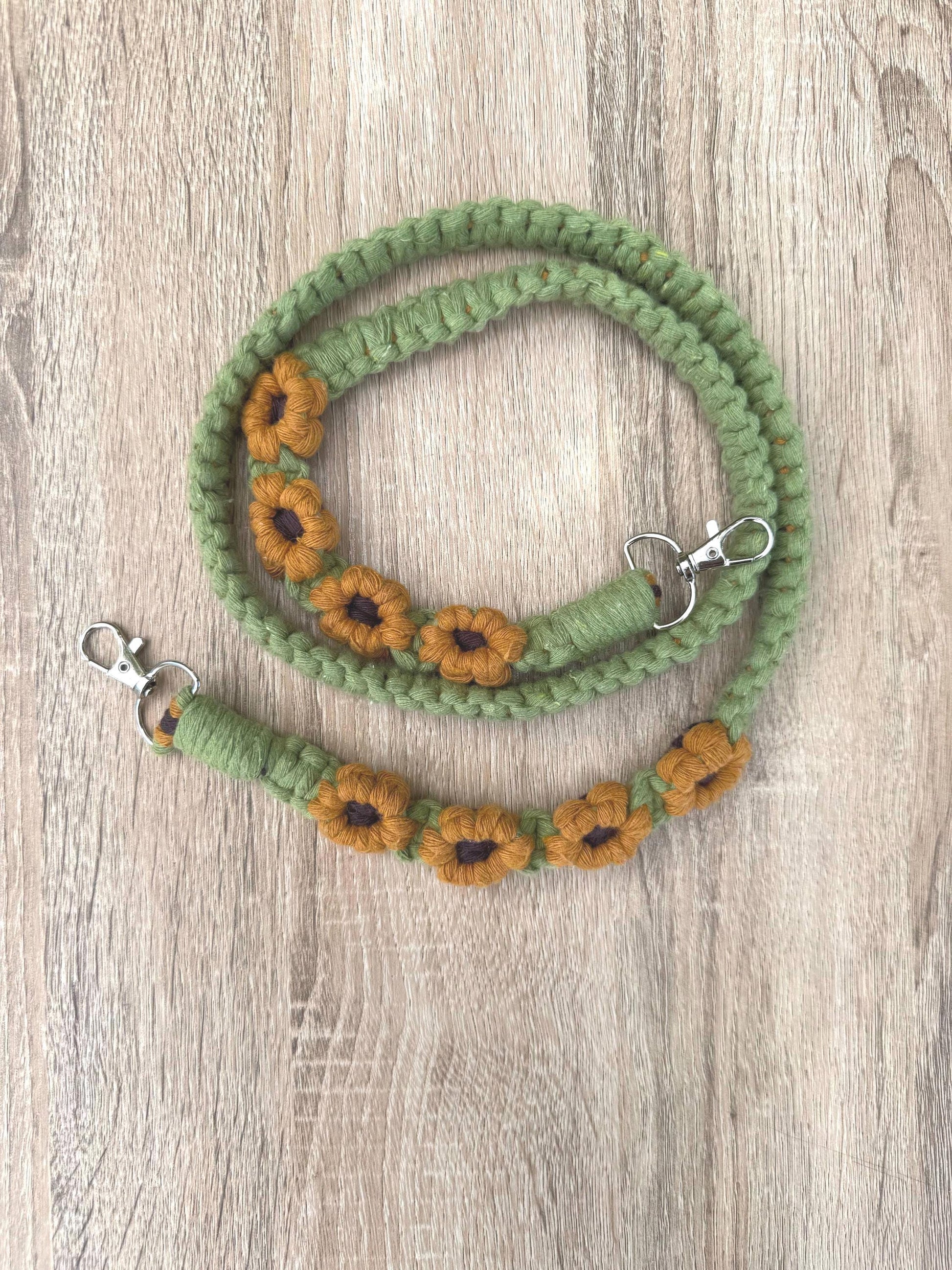 Green macrame strap with sunflower designs on a wooden surface