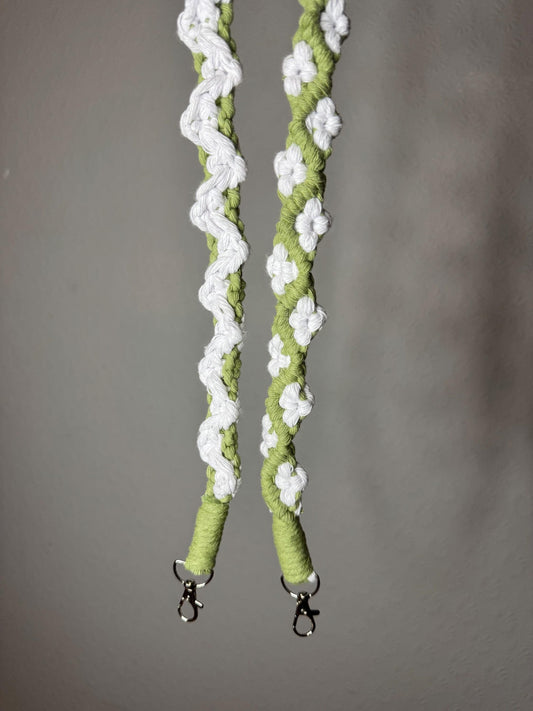 Green and white macrame strap with metal clasps on a gray background