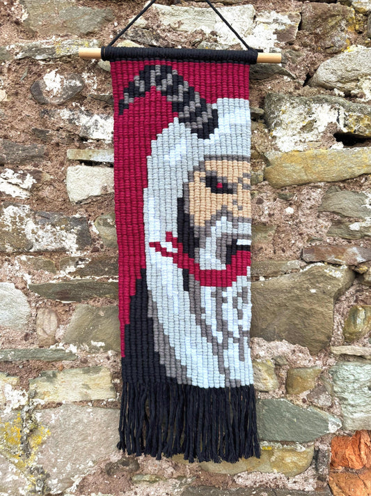 Krampus pixel macrame wall hanging on a stone wall