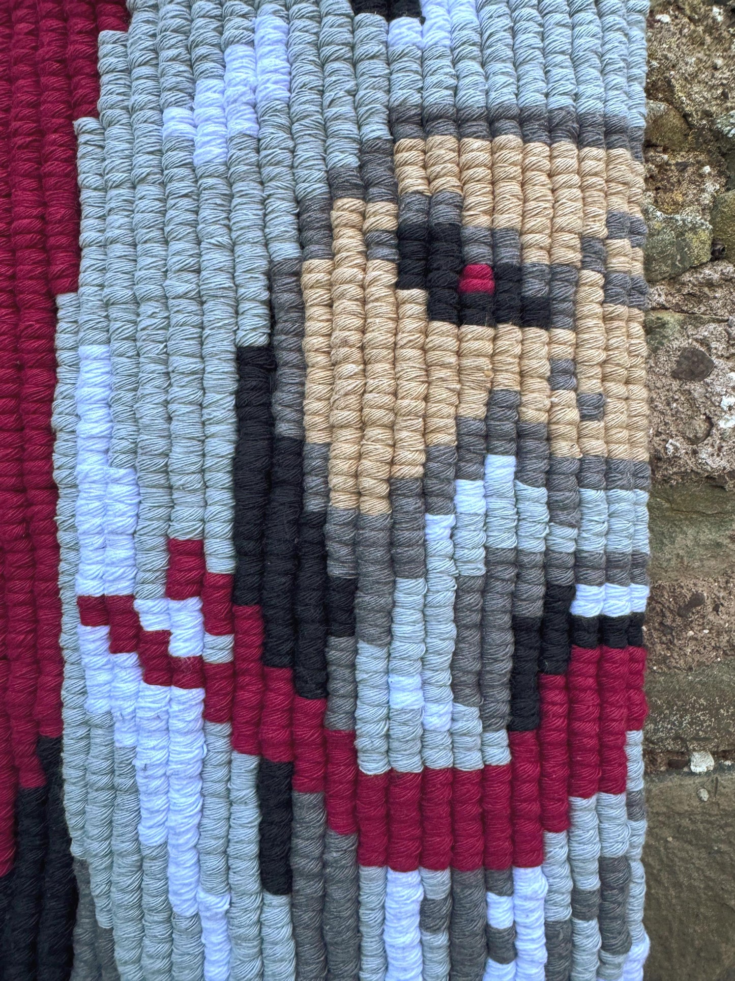 Textile art piece with pixelated design on a textured background