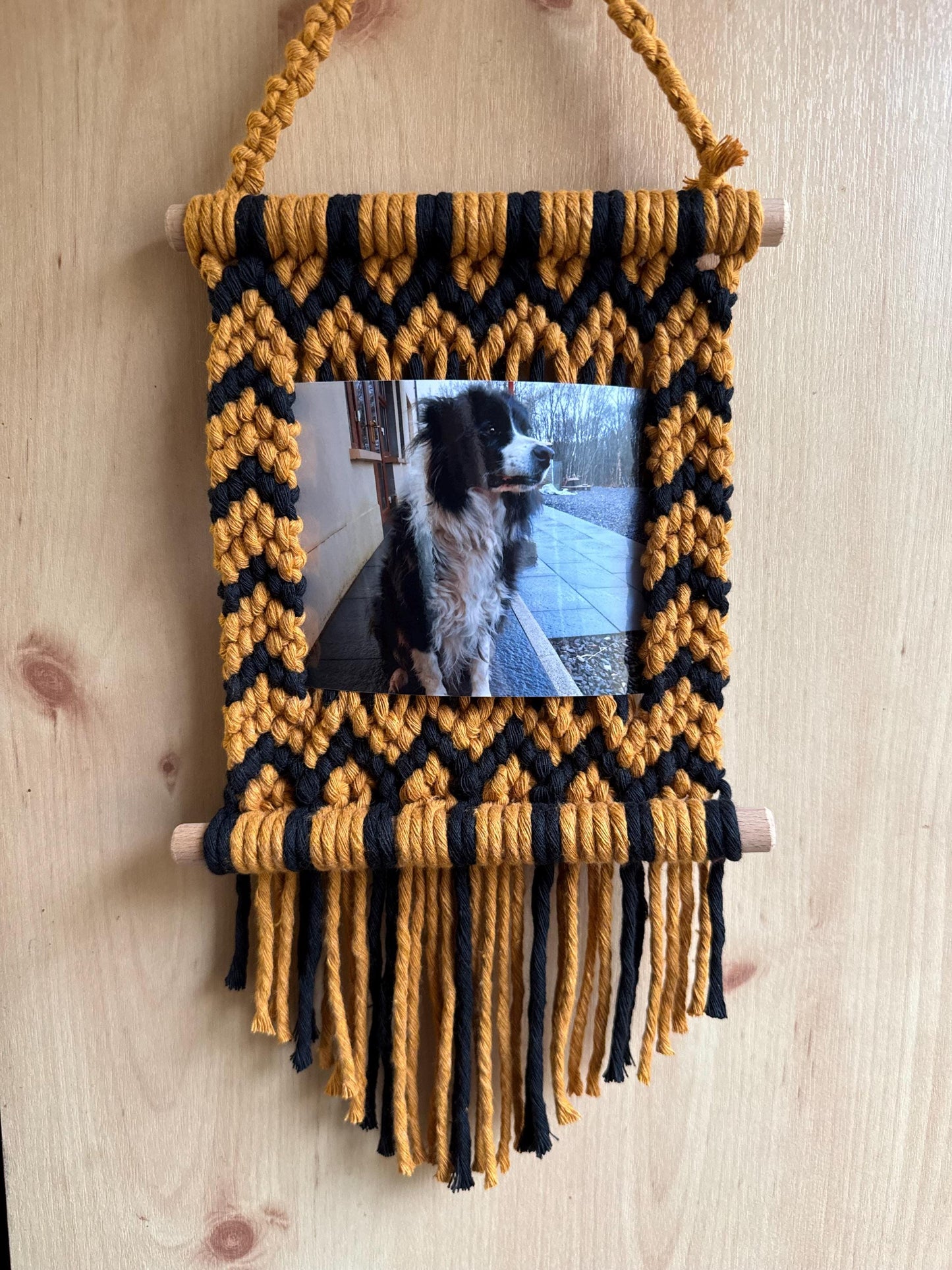 Yellow and black zig-zags macrame photo frame with a picture of a dog on a wooden surface