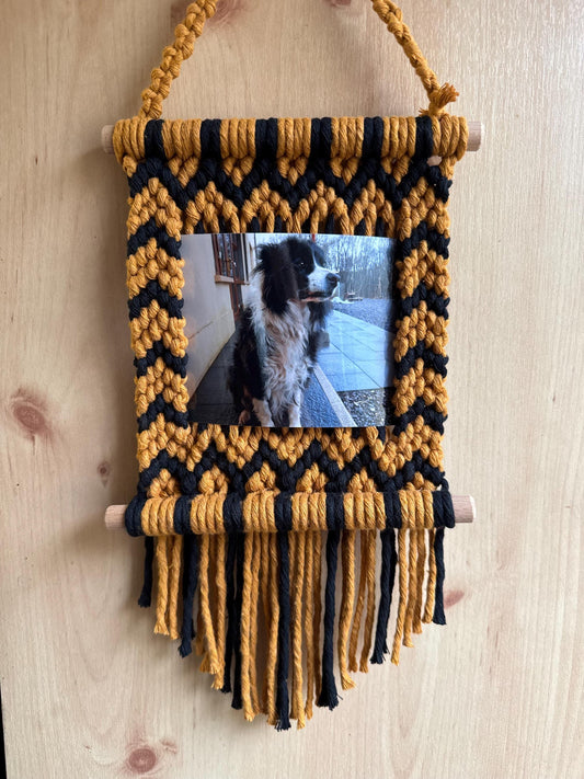 Yellow and black zig-zags macrame photo frame with a picture of a dog on a wooden surface