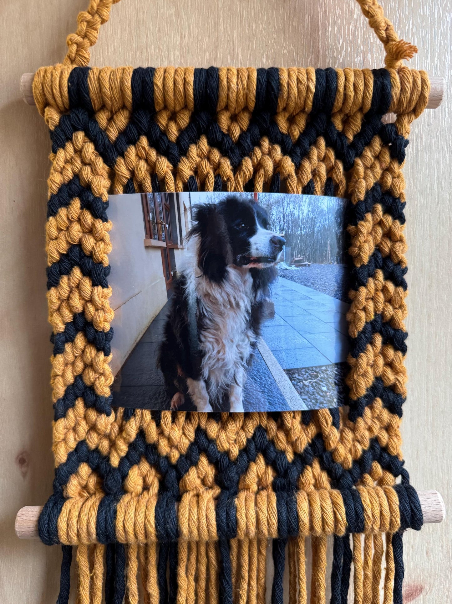 Macrame wall hanging with a picture of a dog on a wooden surface