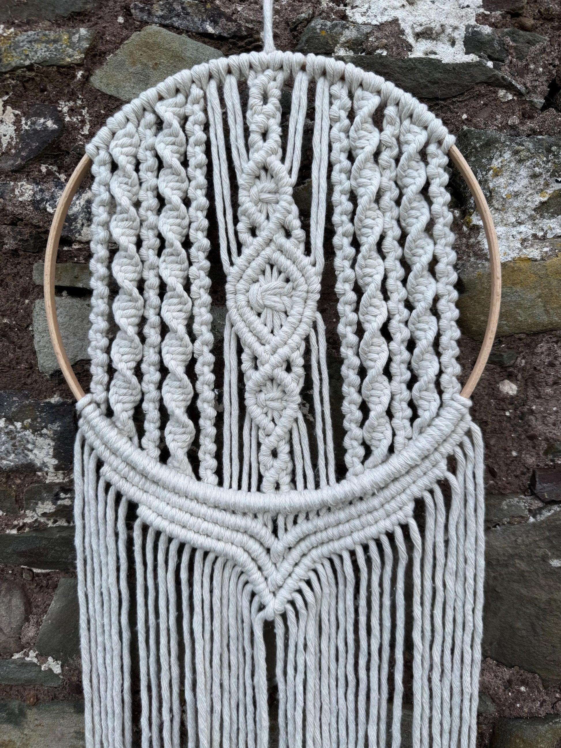 Macrame wall hanging against a stone wall background