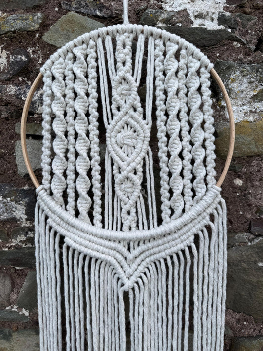 Macrame wall hanging against a stone wall background