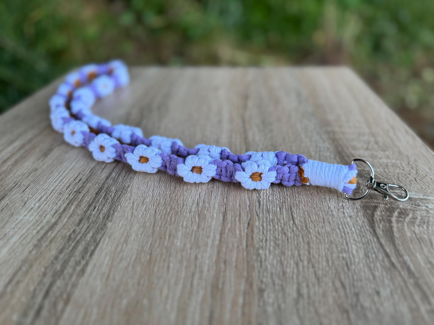 Purple floral lanyard with a keychain on a wooden surface