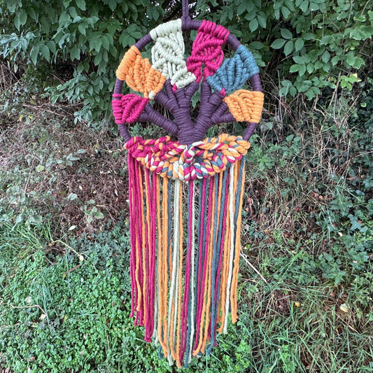 Colorful woven dreamcatcher against a natural green background