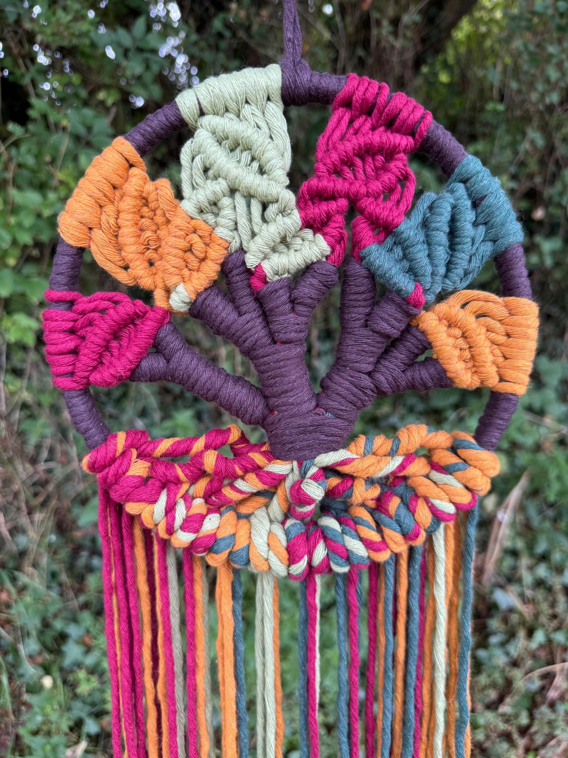 Colorful macrame wall hanging with leaves against a natural background