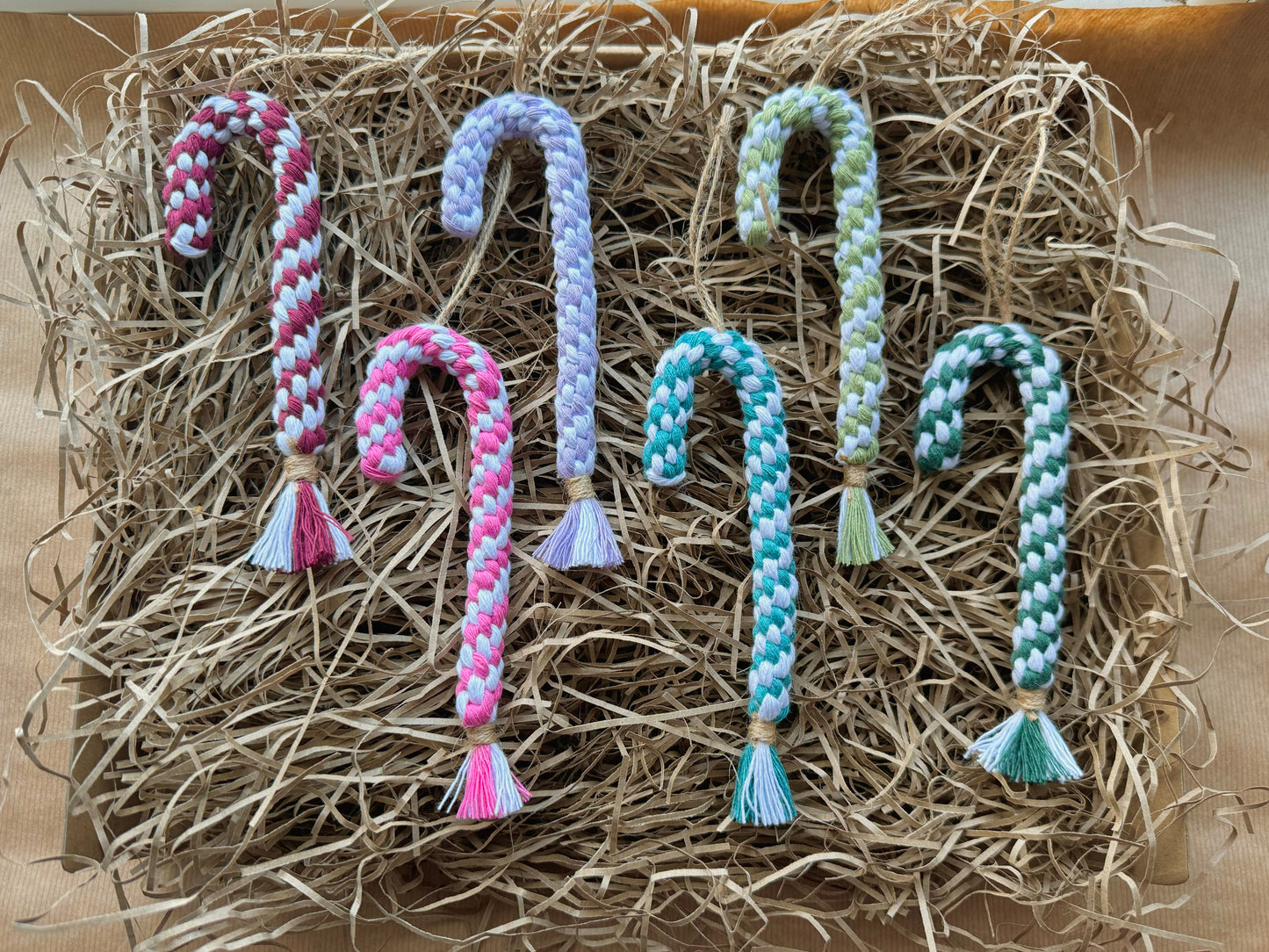 Set of braided candy cane-shaped ornaments on a bed of straw.