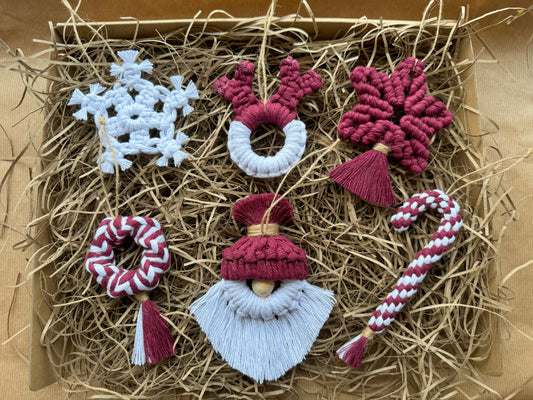 Set of decorative burgundy Christmas ornaments including a snowflake, reindeer, gnome, and candy cane on straw.