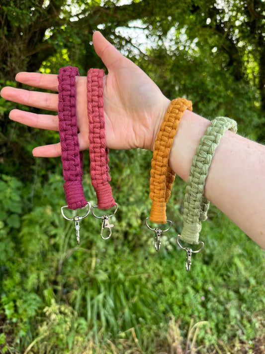 Hand holding four colorful keychains with a green outdoor background
