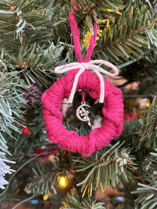 Burgundy yarn-wrapped ornament with a silver fairy charm on a Christmas tree.