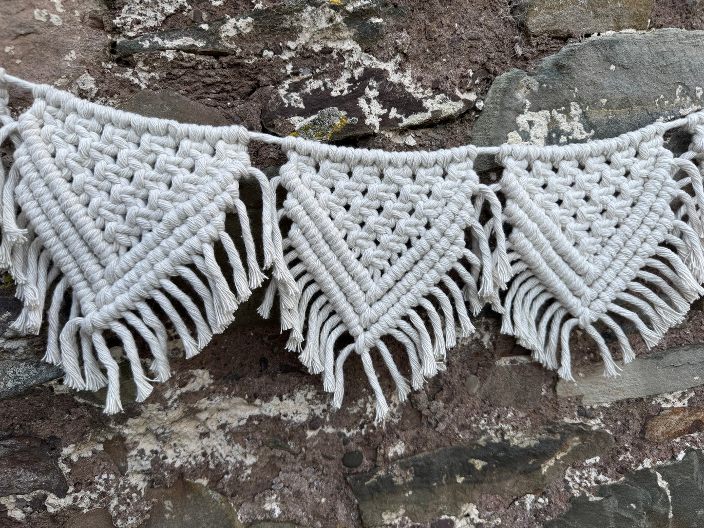 Close-up of macrame flags against a stone wall