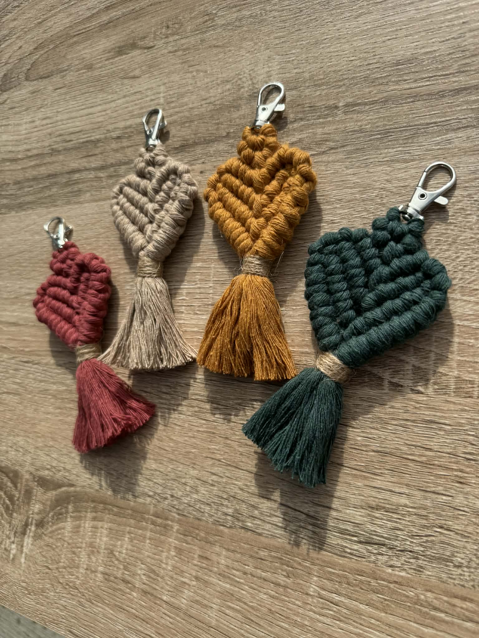 Four macrame keychains in different colors on a wooden surface