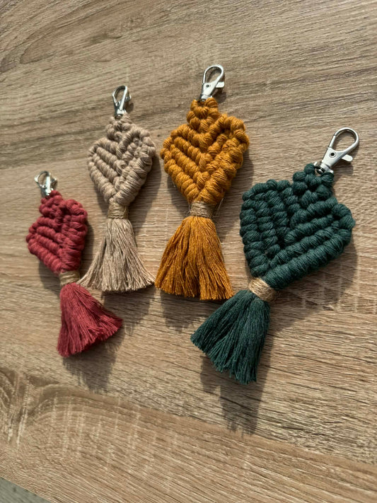 Four macrame keychains in different colors on a wooden surface