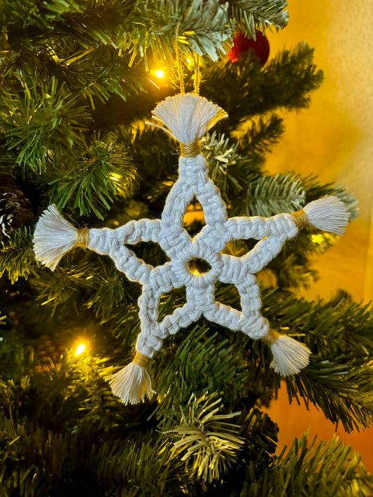 White macrame star ornament on a decorated Christmas tree with warm glow.