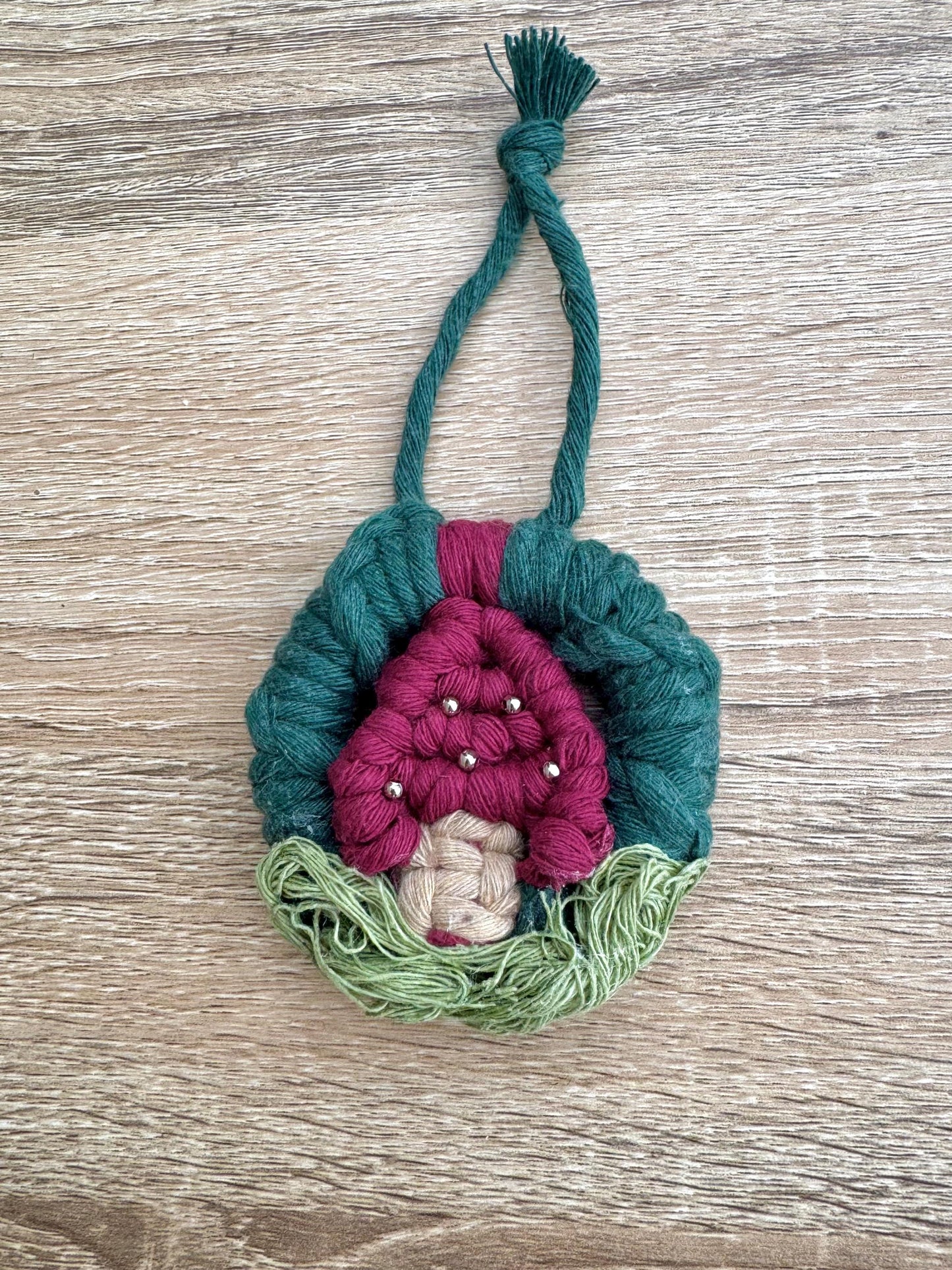 Handmade mushroom ornament with pink interior and green exterior on a wooden surface