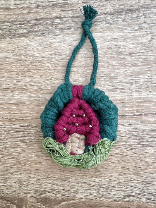 Handmade mushroom ornament with pink interior and green exterior on a wooden surface