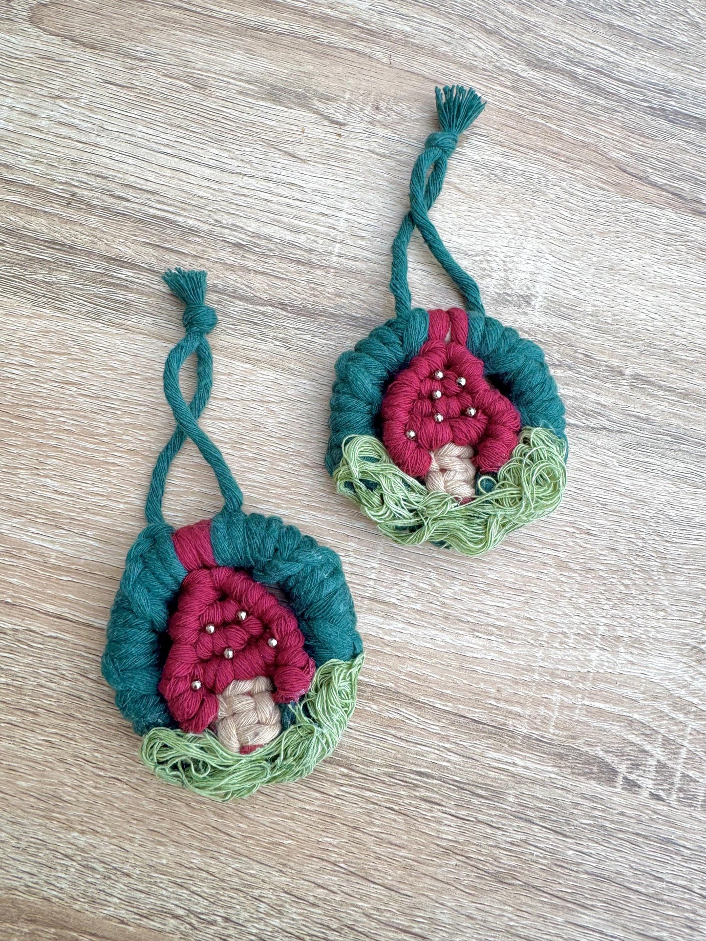 Two handcrafted decorative items with pink centers and green exteriors on a wooden surface.