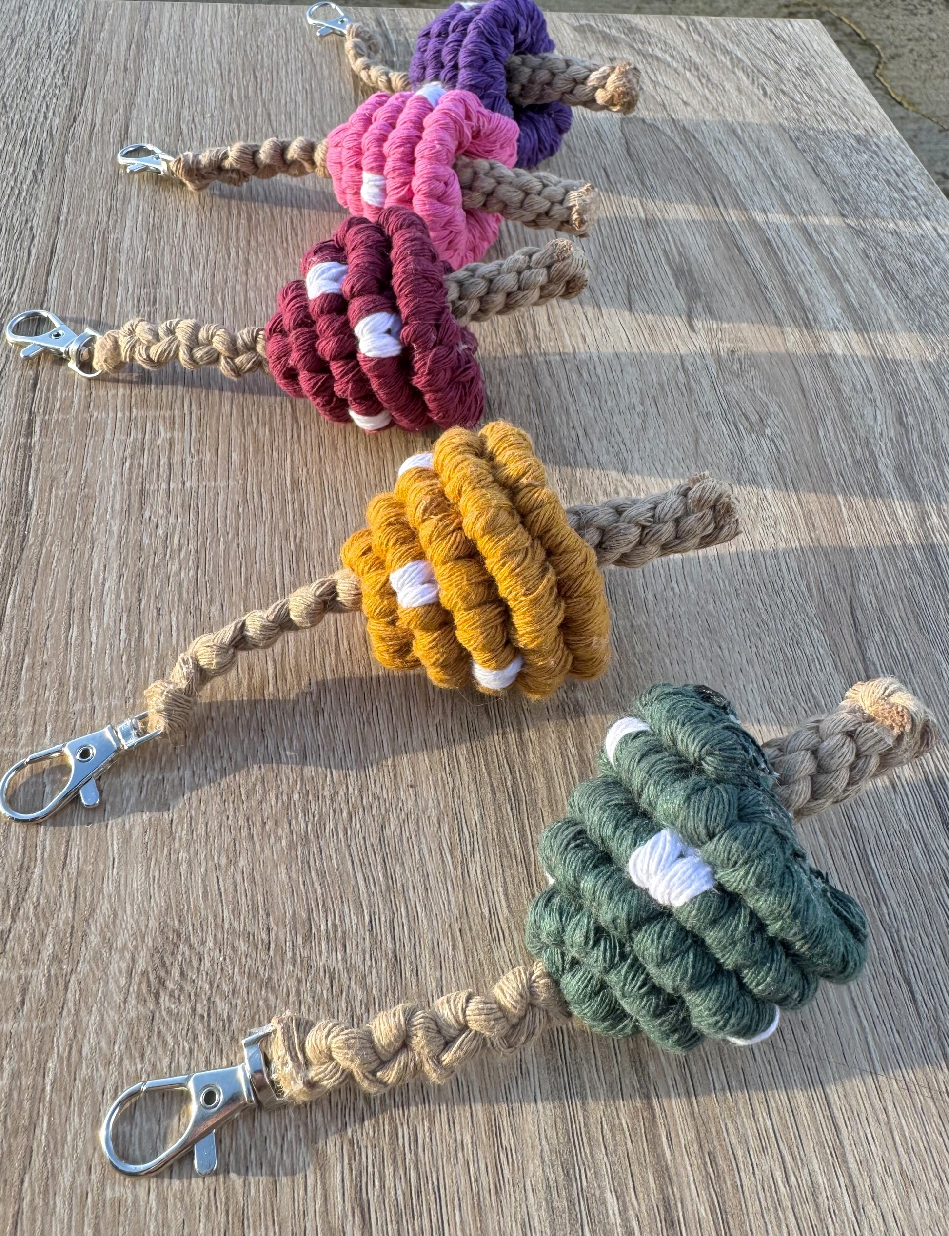 Five colorful macrame mushrooms with keychains on a wooden surface