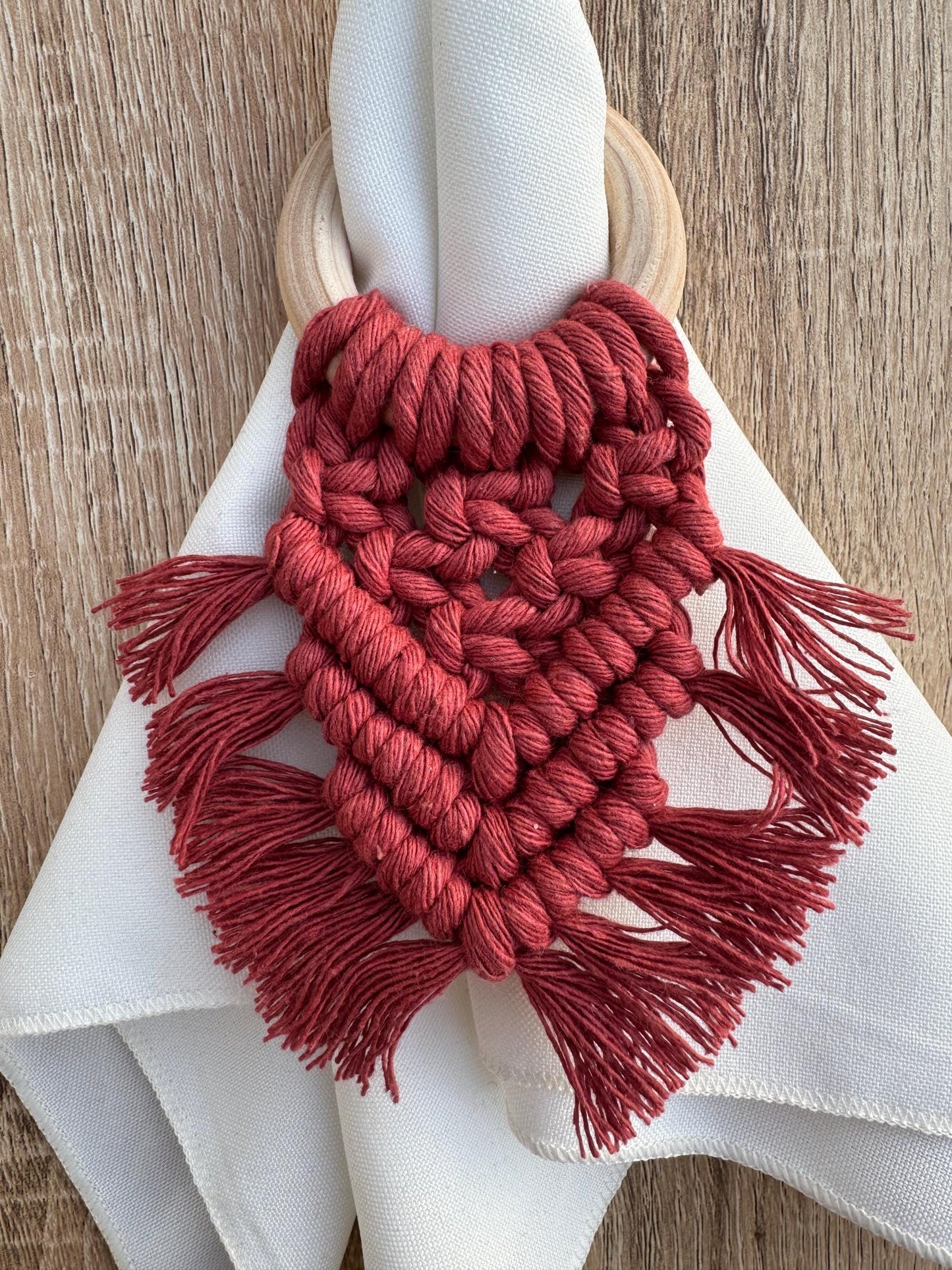 terracotta /burnt orange wooden napkin ring holding a napkin on a wooden surface