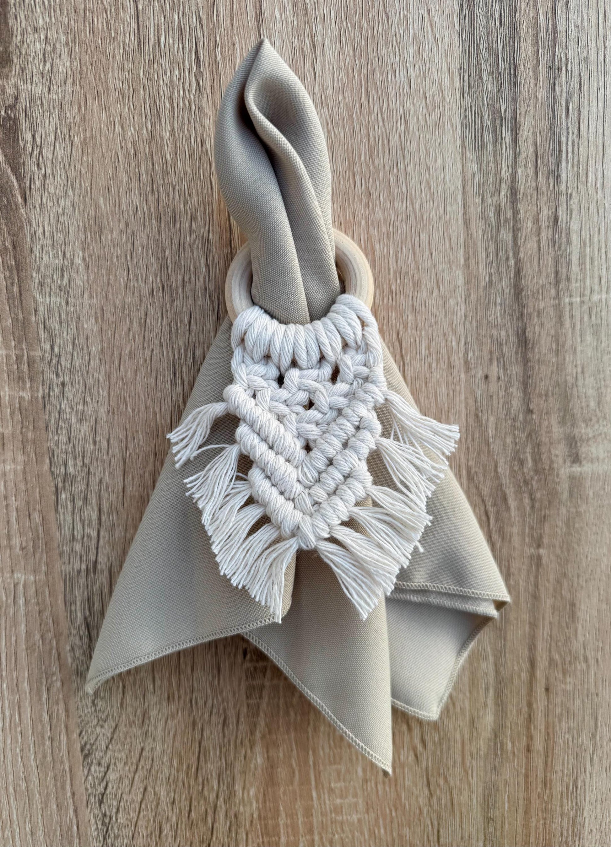 beige napkin with a white macrame holder on a wooden surface