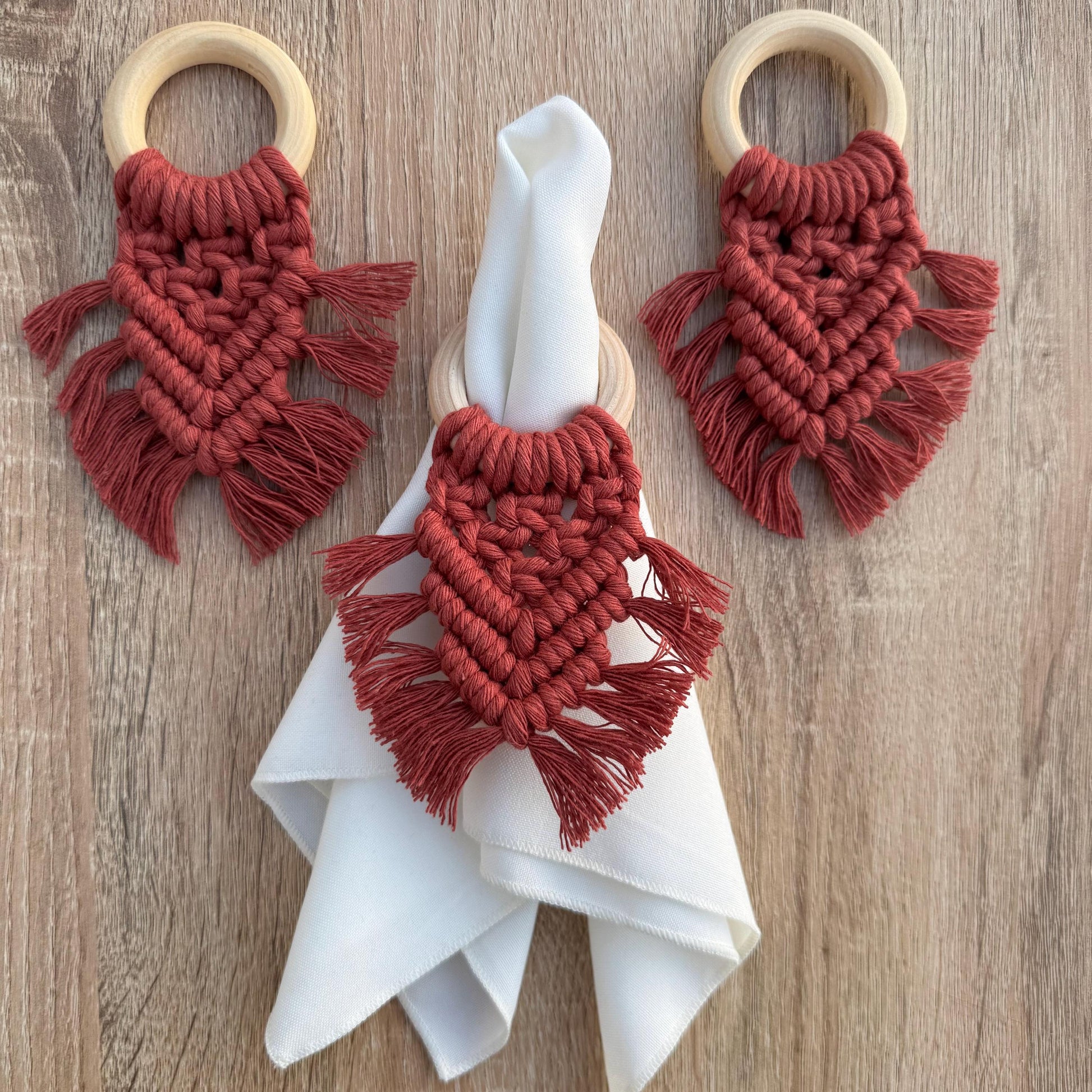 terracotta macrame wooden napkin rings with a napkin on a wooden surface